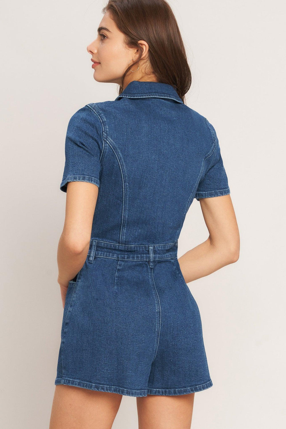 A washed denim romper featuring collar, front zipper closure, short sleeve and pockets