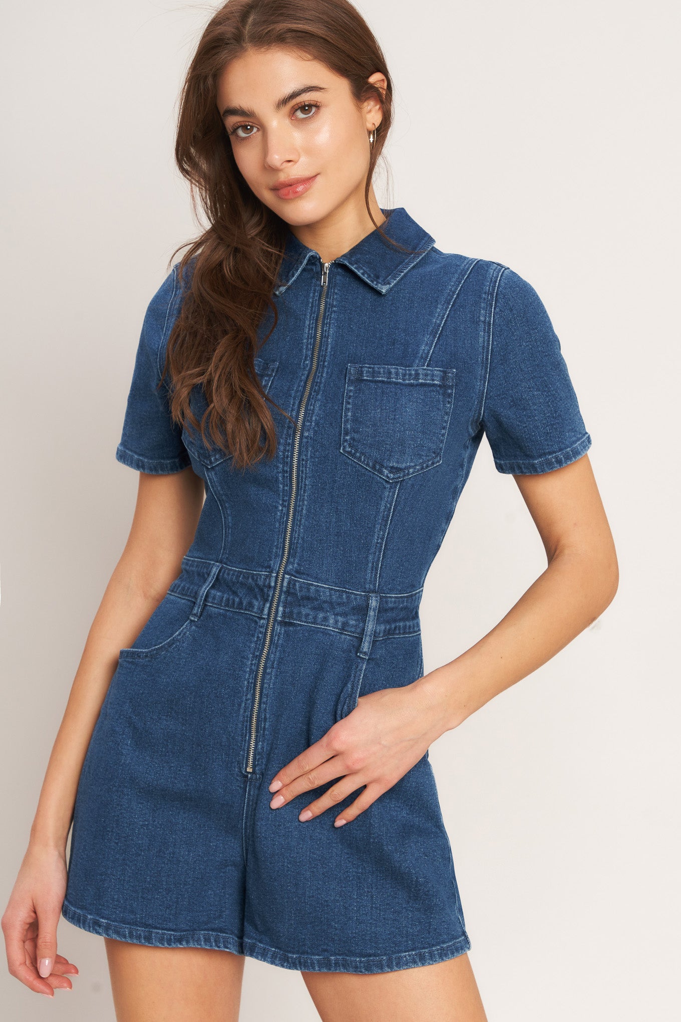 A washed denim romper featuring collar, front zipper closure, short sleeve and pockets