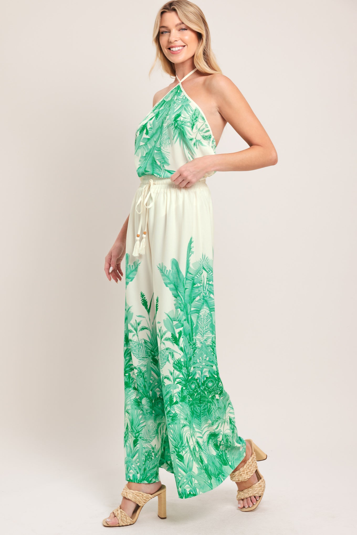 Woman wearing green and white tropical leaf patterned wide-leg pants with elastic waist and front tie | Flying Tomato