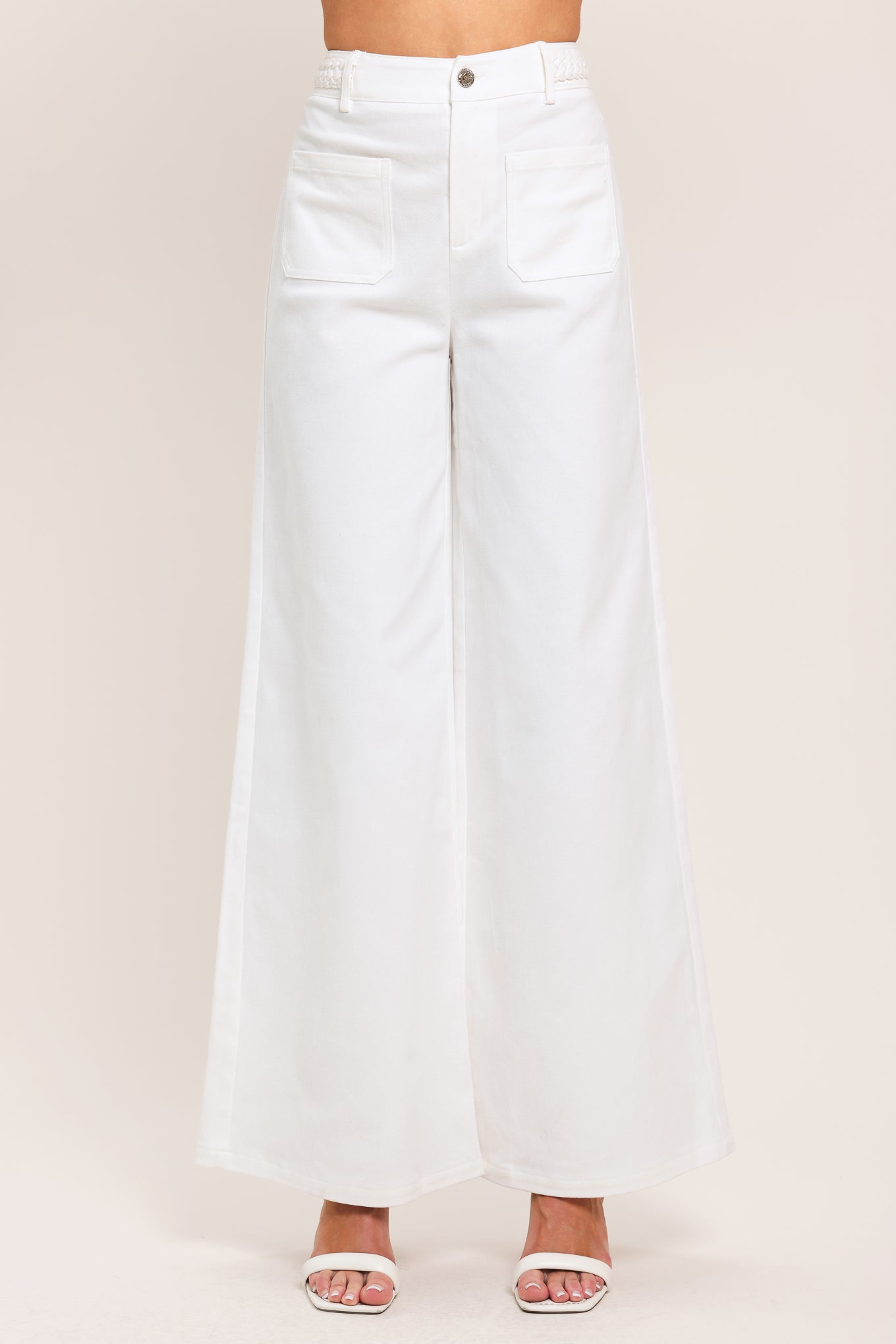 Woman wearing white wide-leg pants with front closure and braided detail waistband | Flying Tomato