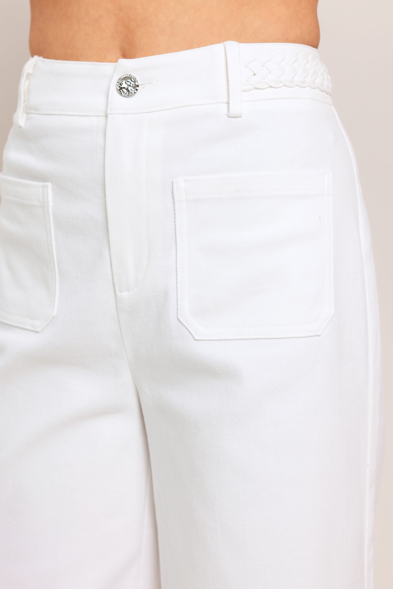 Woman wearing white wide-leg pants with front closure and braided detail waistband | Flying Tomato