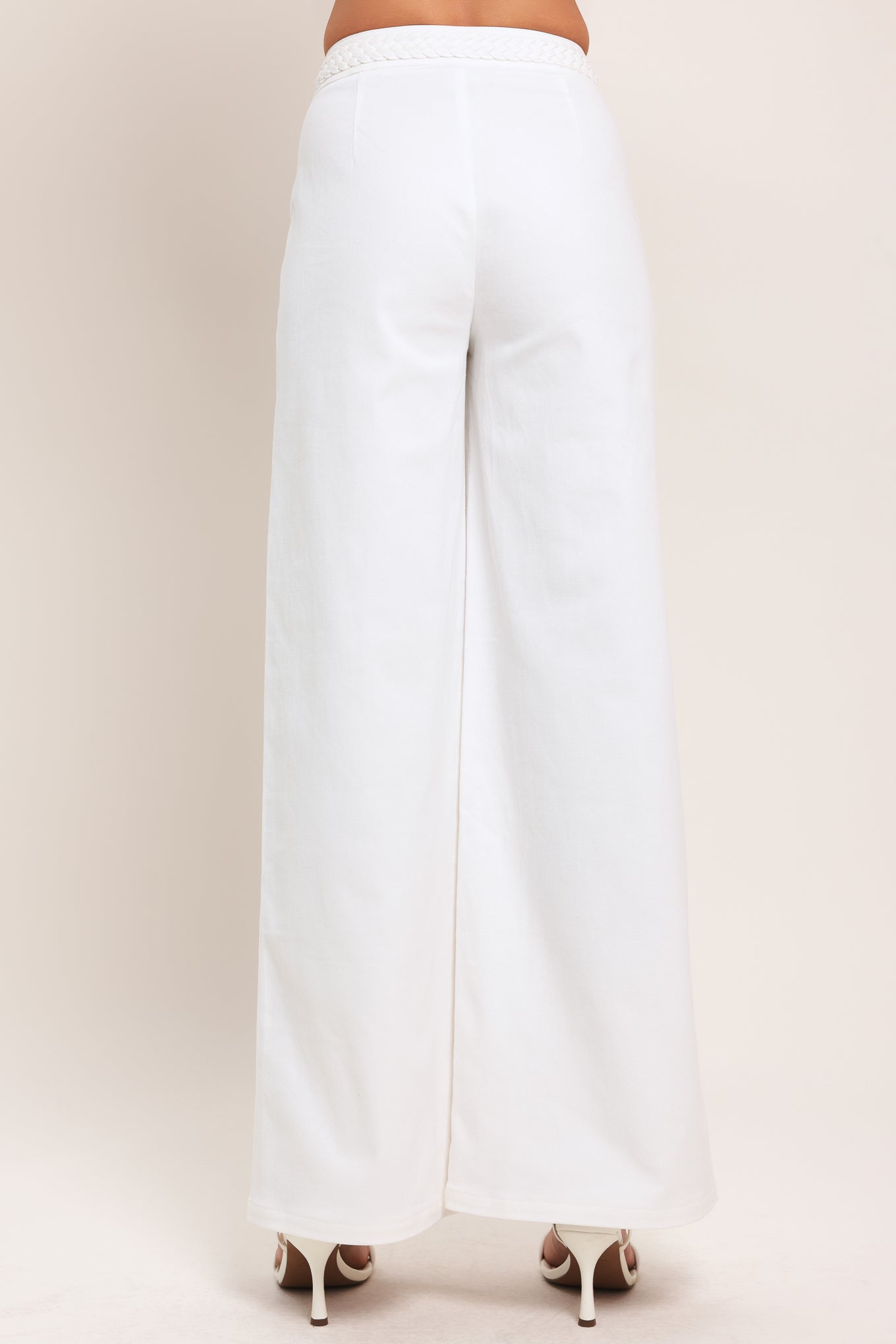 Woman wearing white wide-leg pants with front closure and braided detail waistband | Flying Tomato