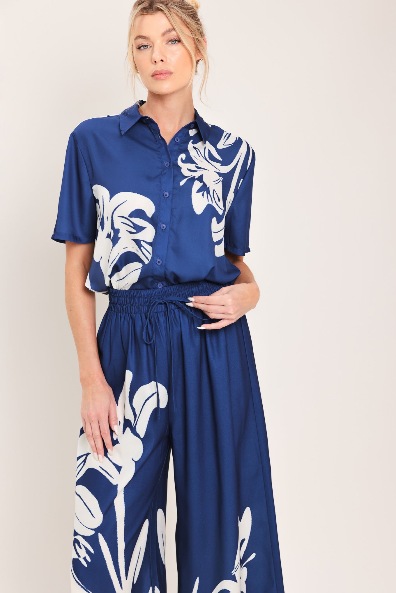 Woman wearing a navy blue with white floral print wide leg pant featuring an elastic waist with tie | Flying Tomato