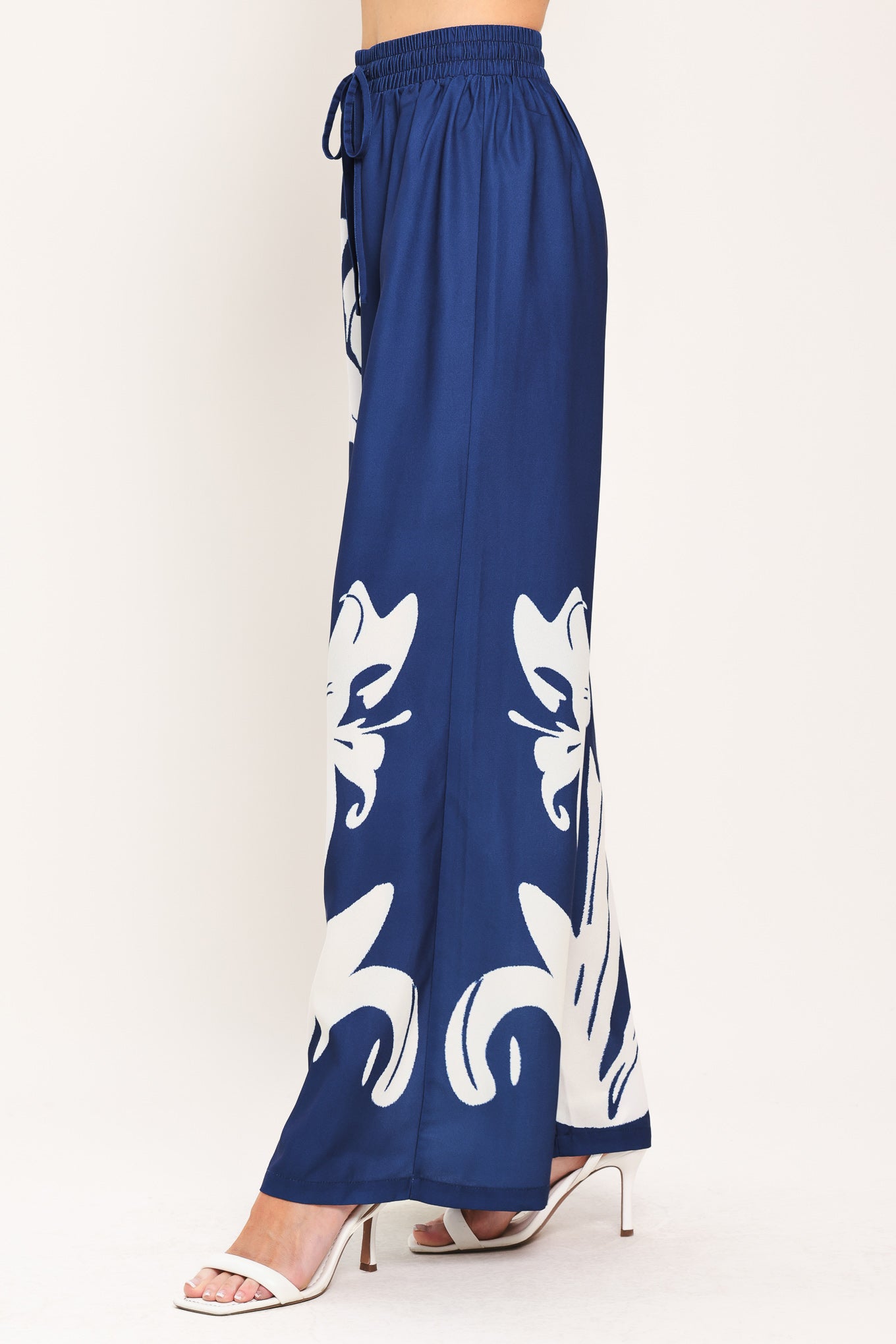 Woman wearing a navy blue with white floral print wide leg pant featuring an elastic waist with tie | Flying Tomato