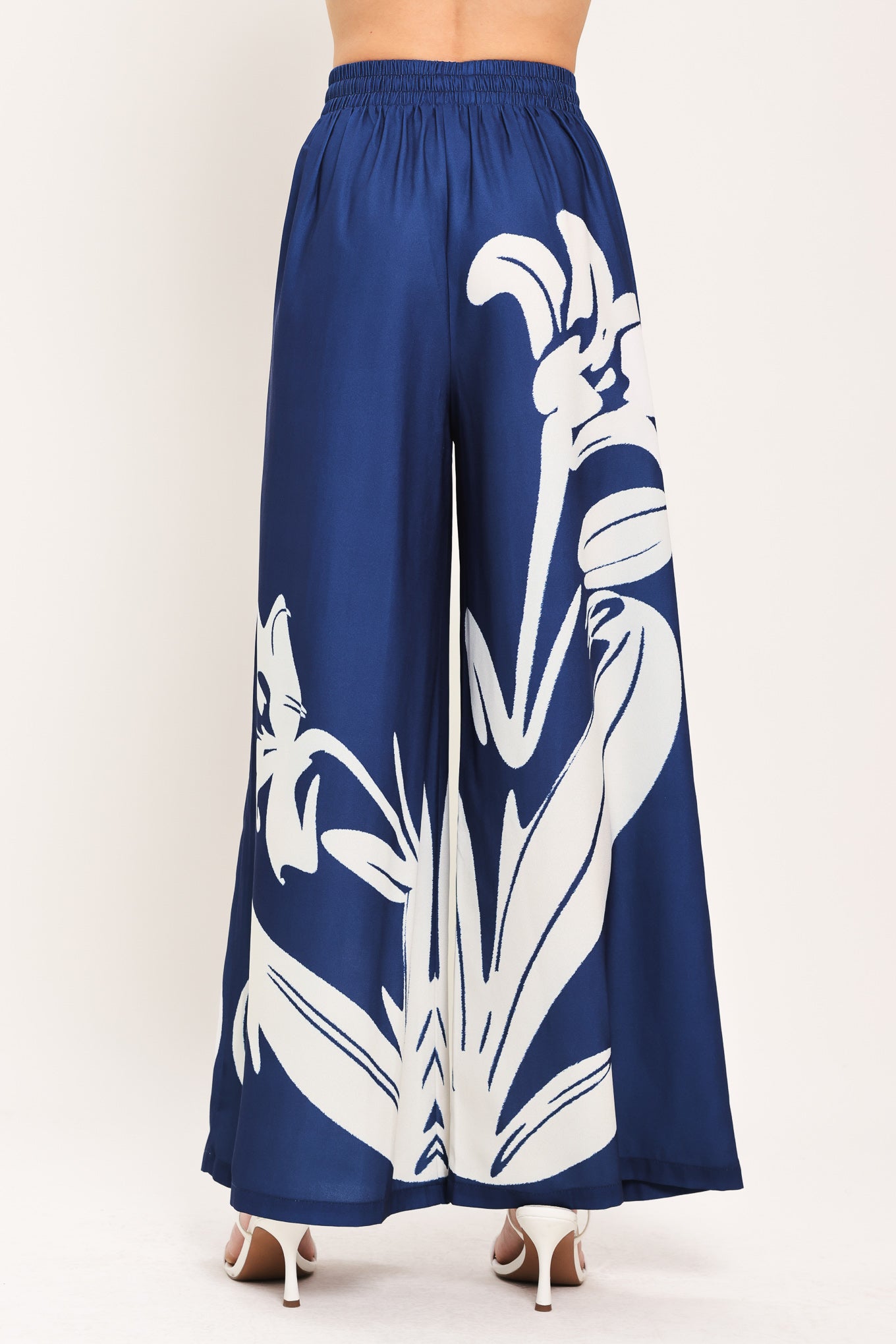 Woman wearing a navy blue with white floral print wide leg pant featuring an elastic waist with tie | Flying Tomato