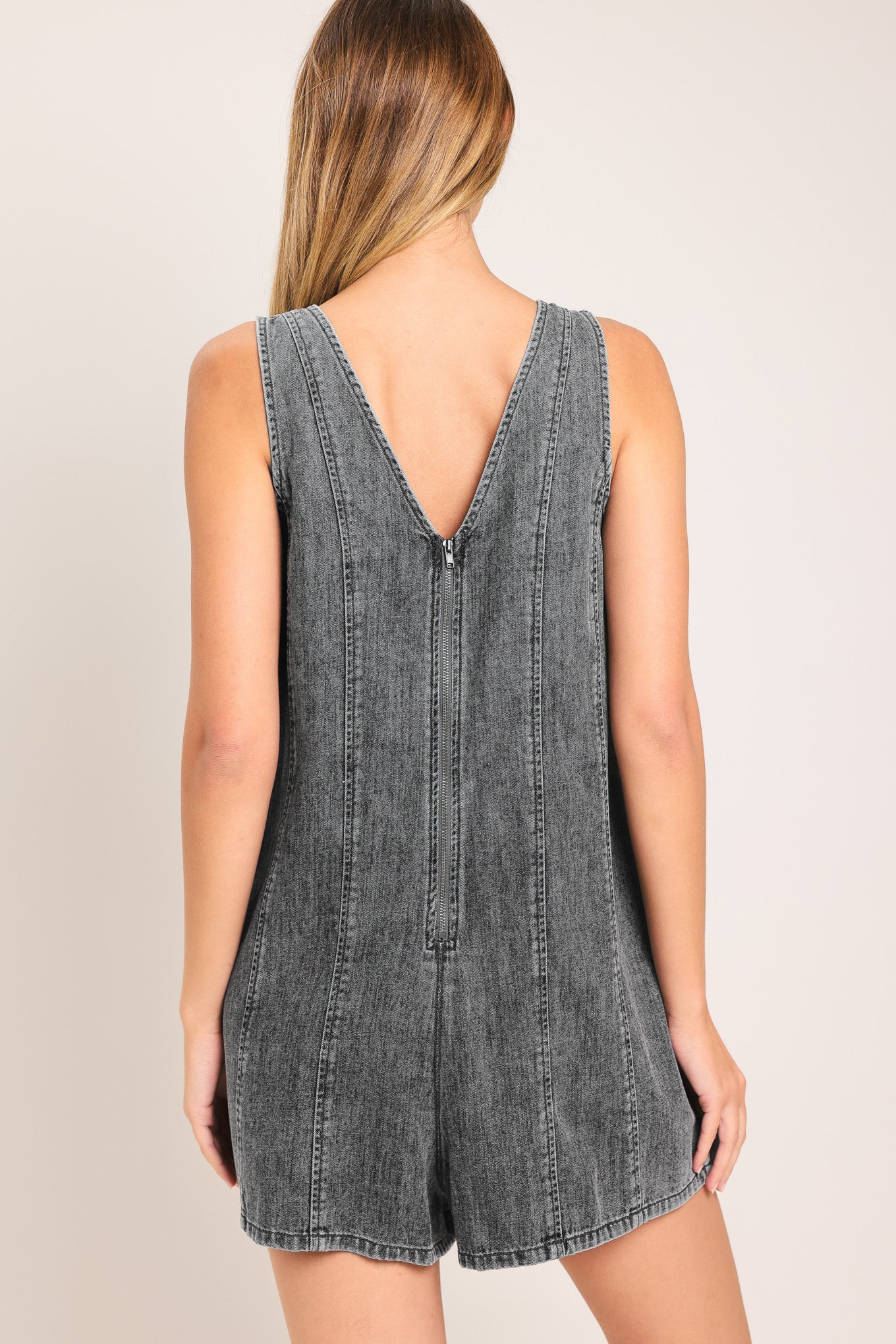 Woman wearing a lightweight denim romper with V neckline and zipper back closure | Flying Tomato