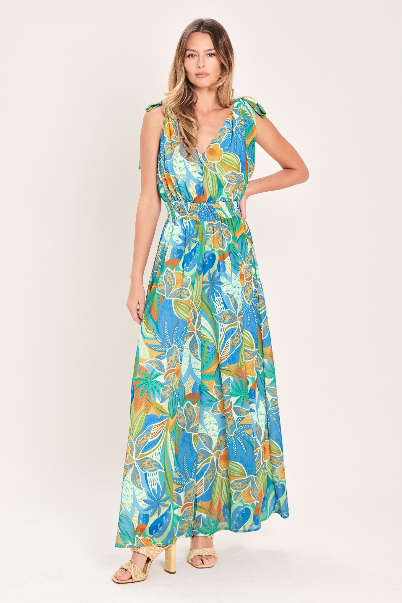 Woman wearing a blue multicolored patterned woven jumpsuit featuring V neckline, shoulder ties, smocked waistband and wide leg | Flying Tomato