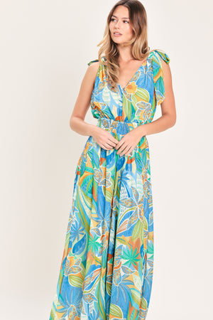 Woman wearing a blue multicolored patterned woven jumpsuit featuring V neckline, shoulder ties, smocked waistband and wide leg | Flying Tomato