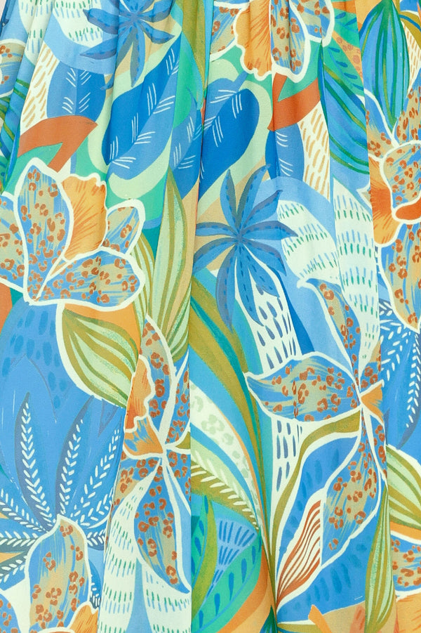 Close up of a blue multicolored patterned woven jumpsuit featuring V neckline, shoulder ties, smocked waistband and wide leg | Flying Tomato