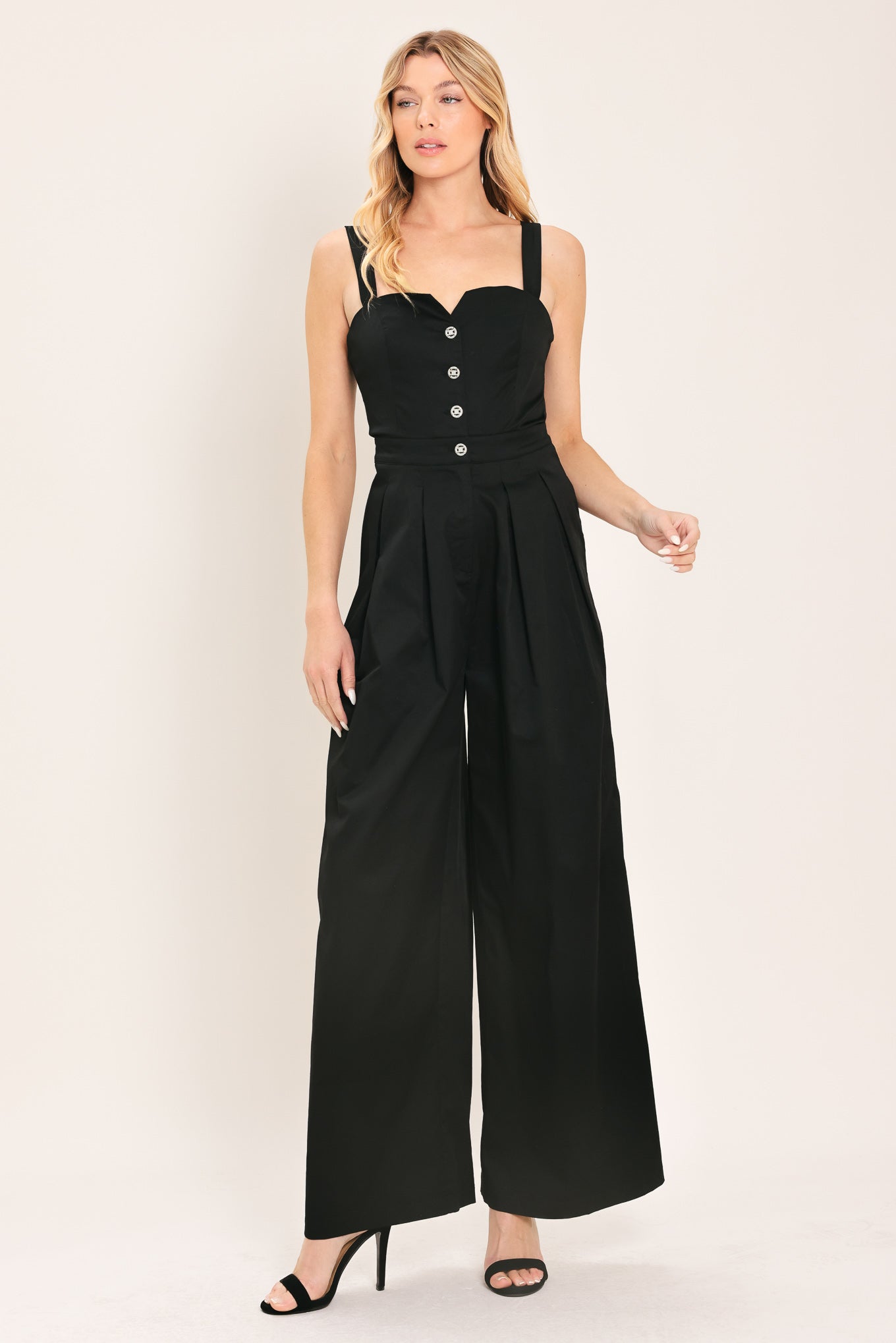 Woman wearing a black wide leg jumpsuit with buttons | Flying Tomato