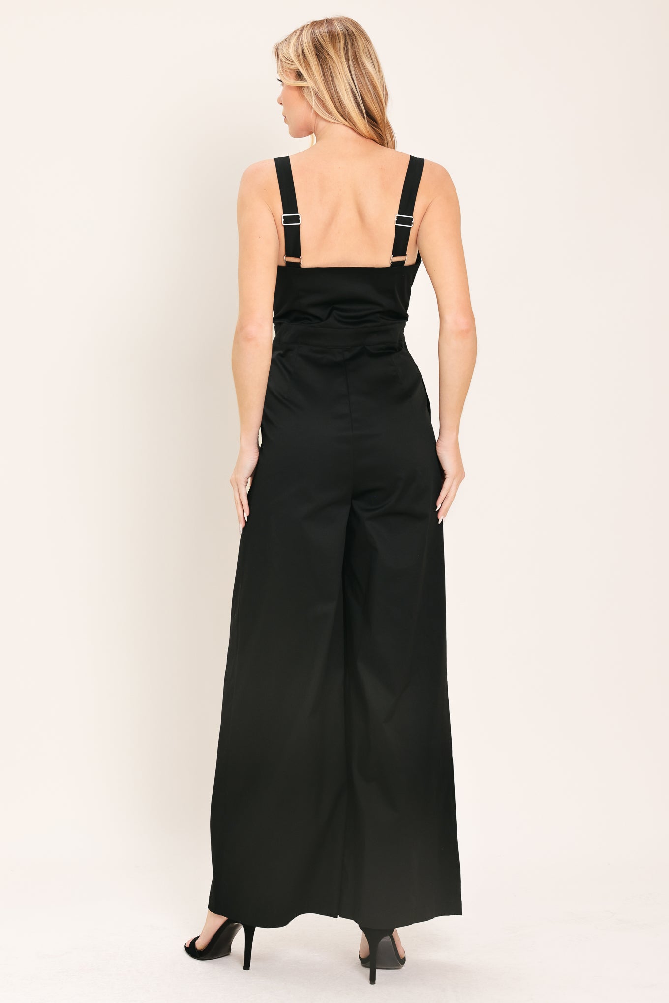 Woman wearing a black wide leg jumpsuit with buttons | Flying Tomato