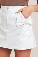 Woman wearing a white denim skort featuring front closure and side bow shaped pocket | Flying Tomato