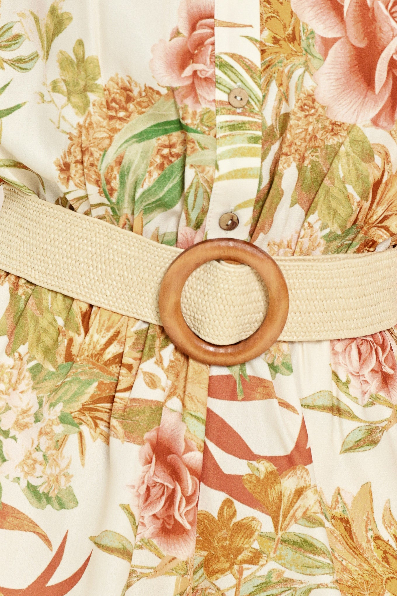Woman wearing a floral romper featuring front button down, cuffed short sleeve with tab, elastic waist and contrasting belt | Flying Tomato