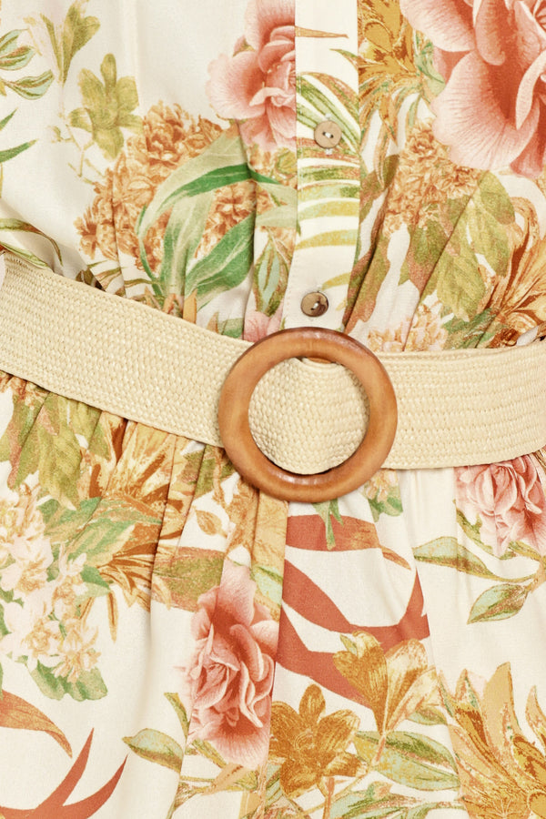 Woman wearing a floral romper featuring front button down, cuffed short sleeve with tab, elastic waist and contrasting belt | Flying Tomato