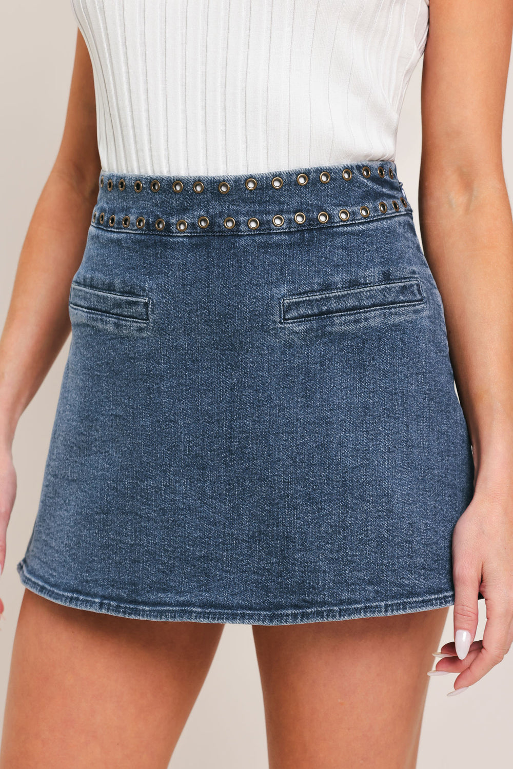 Woman wearing a blue denim skort with studded eyelet waistband denim skort | Flying Tomato