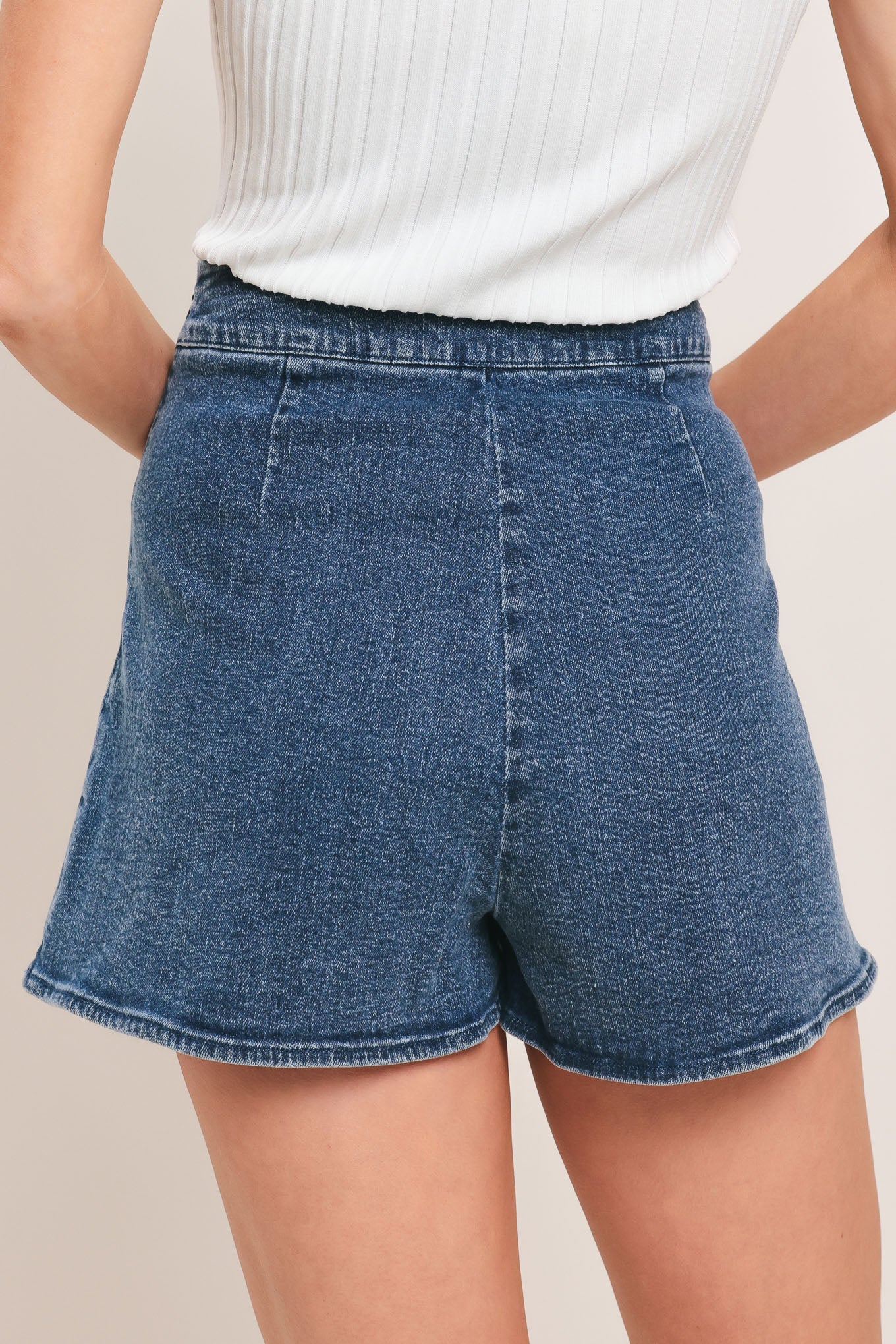 Woman wearing a blue denim skort with studded eyelet waistband denim skort | Flying Tomato