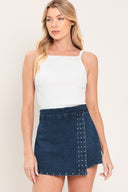 Woman wearing a blue denim skort featuring stud embellished front flap and side zipper closure | Flying Tomato