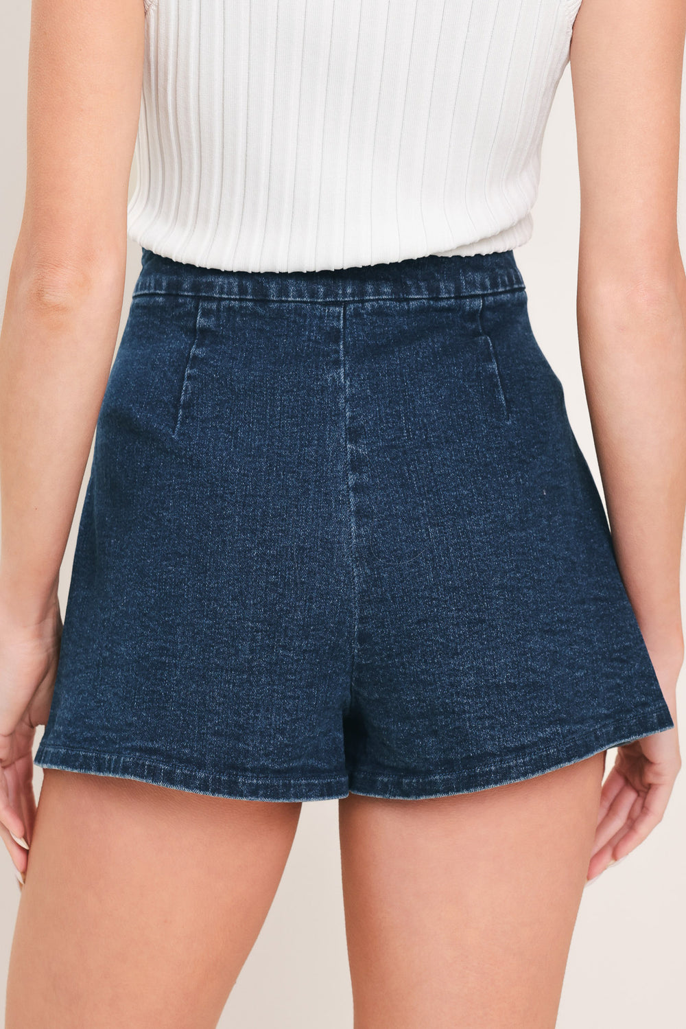 Woman wearing a blue denim skort featuring stud embellished front flap and side zipper closure | Flying Tomato