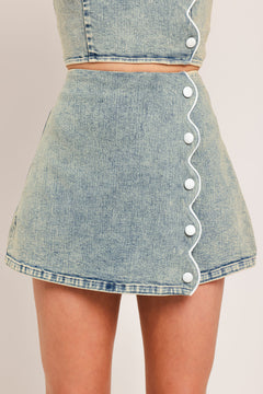 Woman wearing a denim skort featuring scallop edge with button and back zipper closure | Flying Tomato
