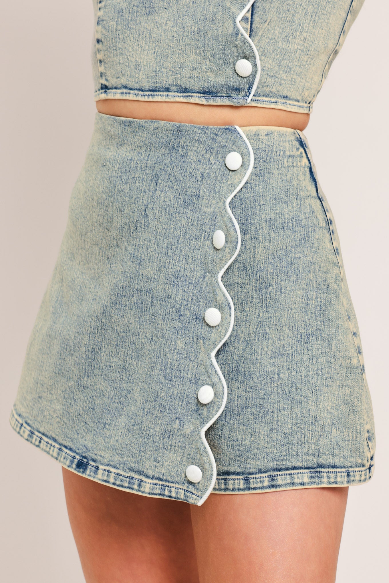 Woman wearing a denim skort featuring scallop edge with button and back zipper closure | Flying Tomato