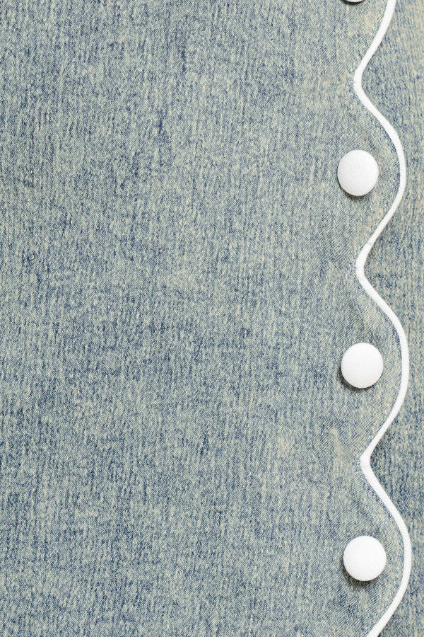 Close-up of denim fabric with a white scallop details and buttons | Flying Tomato