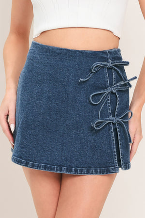 Woman wearing a denim skort featuring side ties and zipper closure | Flying Tomato