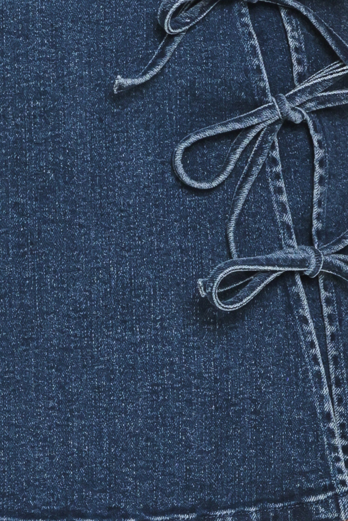 Close-up of a blue denim fabric with a tied bows | Flying Tomato