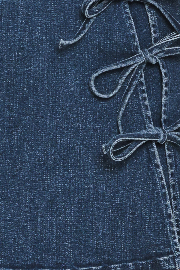 Close-up of a blue denim fabric with a tied bows | Flying Tomato