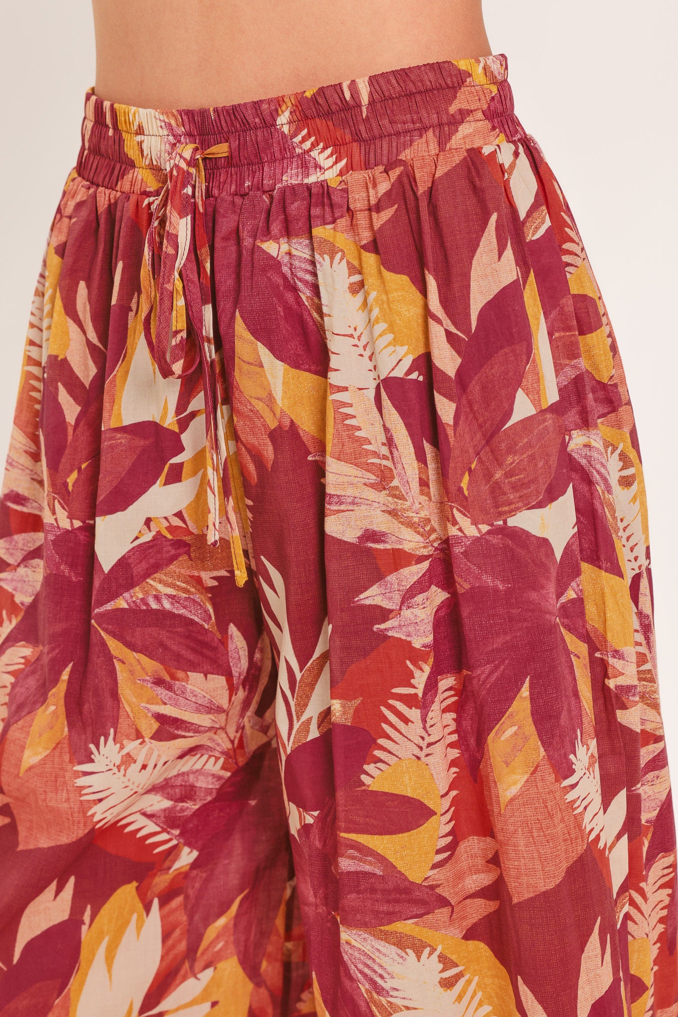 Woman wearing burgundy floral patterned wide leg pants with elastic waist and tie | Flying Tomato