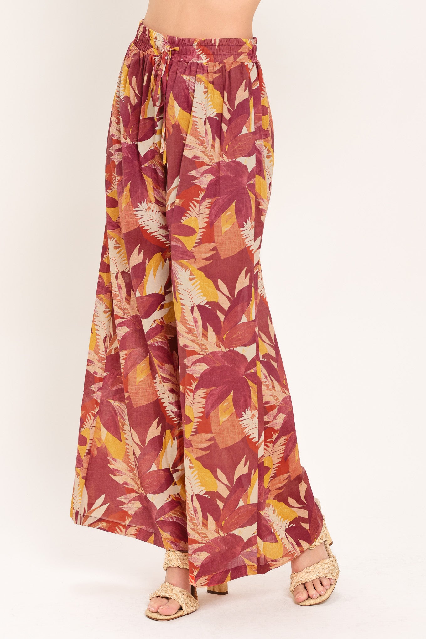 Woman wearing burgundy floral patterned wide leg pants with elastic waist and tie | Flying Tomato
