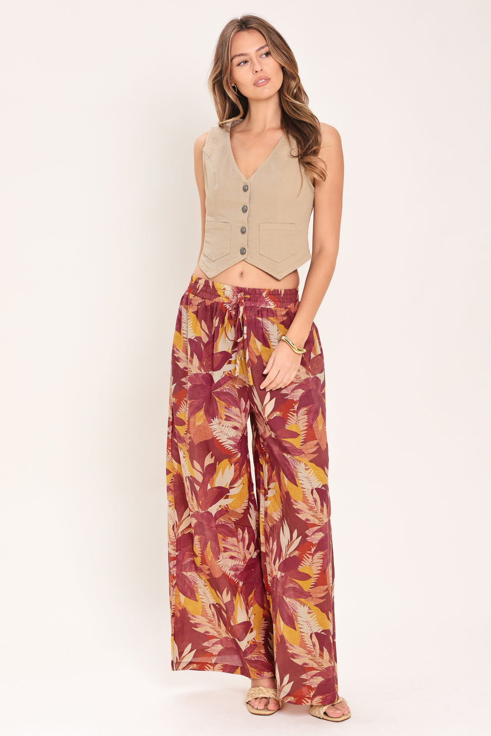 Woman wearing burgundy floral patterned wide leg pants with elastic waist and tie | Flying Tomato