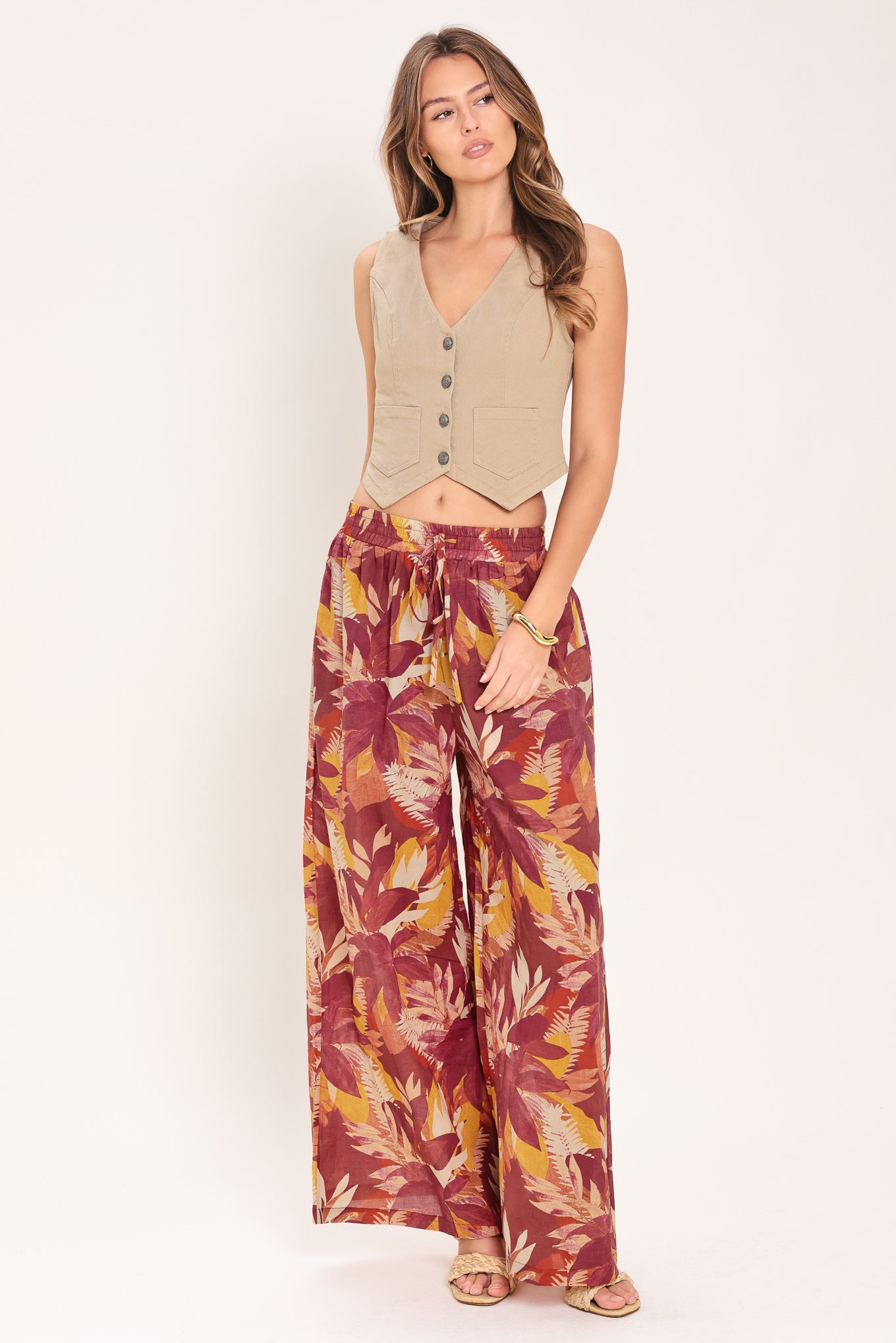 Woman wearing burgundy floral patterned wide leg pants with elastic waist and tie | Flying Tomato