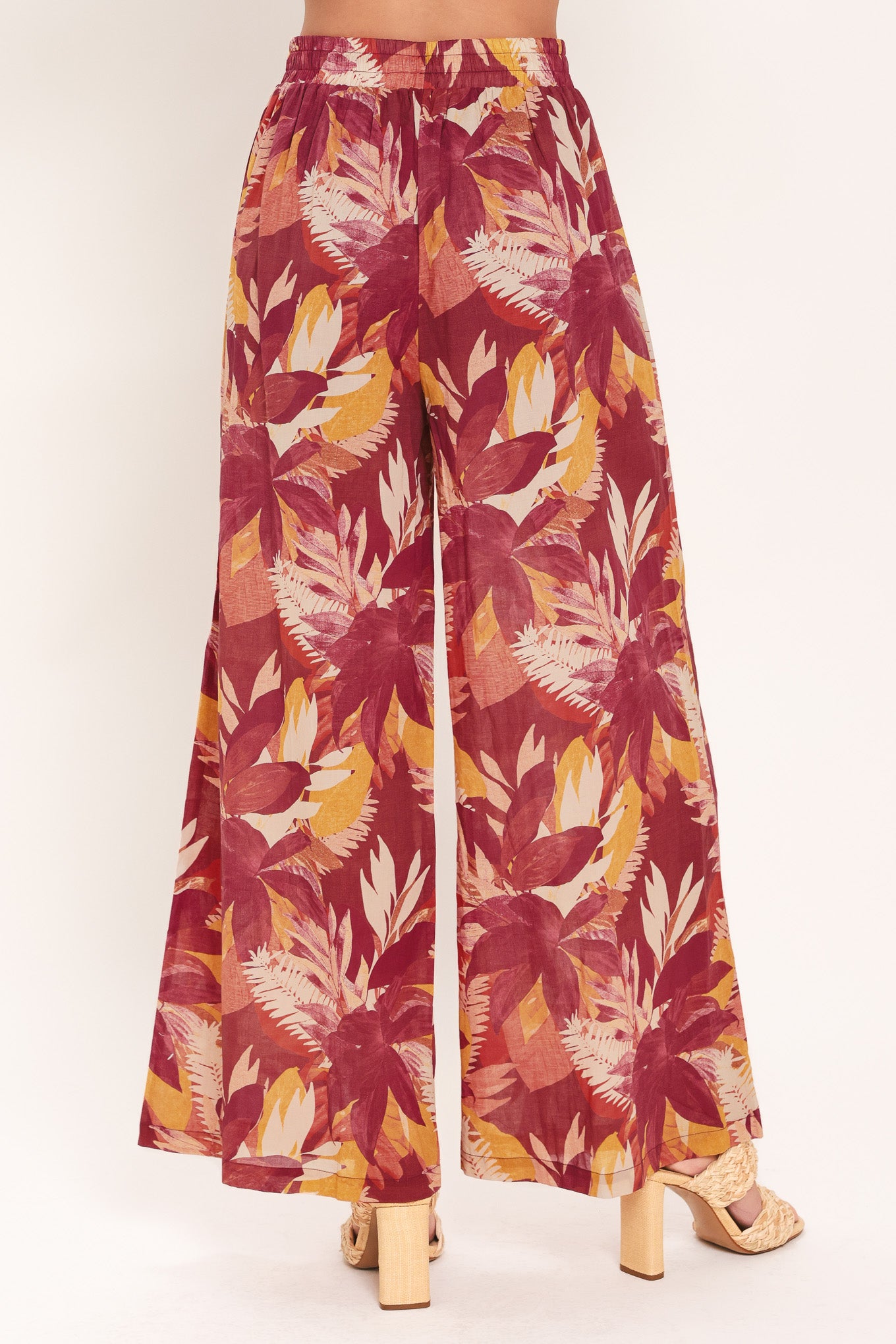 Woman wearing burgundy floral patterned wide leg pants with elastic waist and tie | Flying Tomato