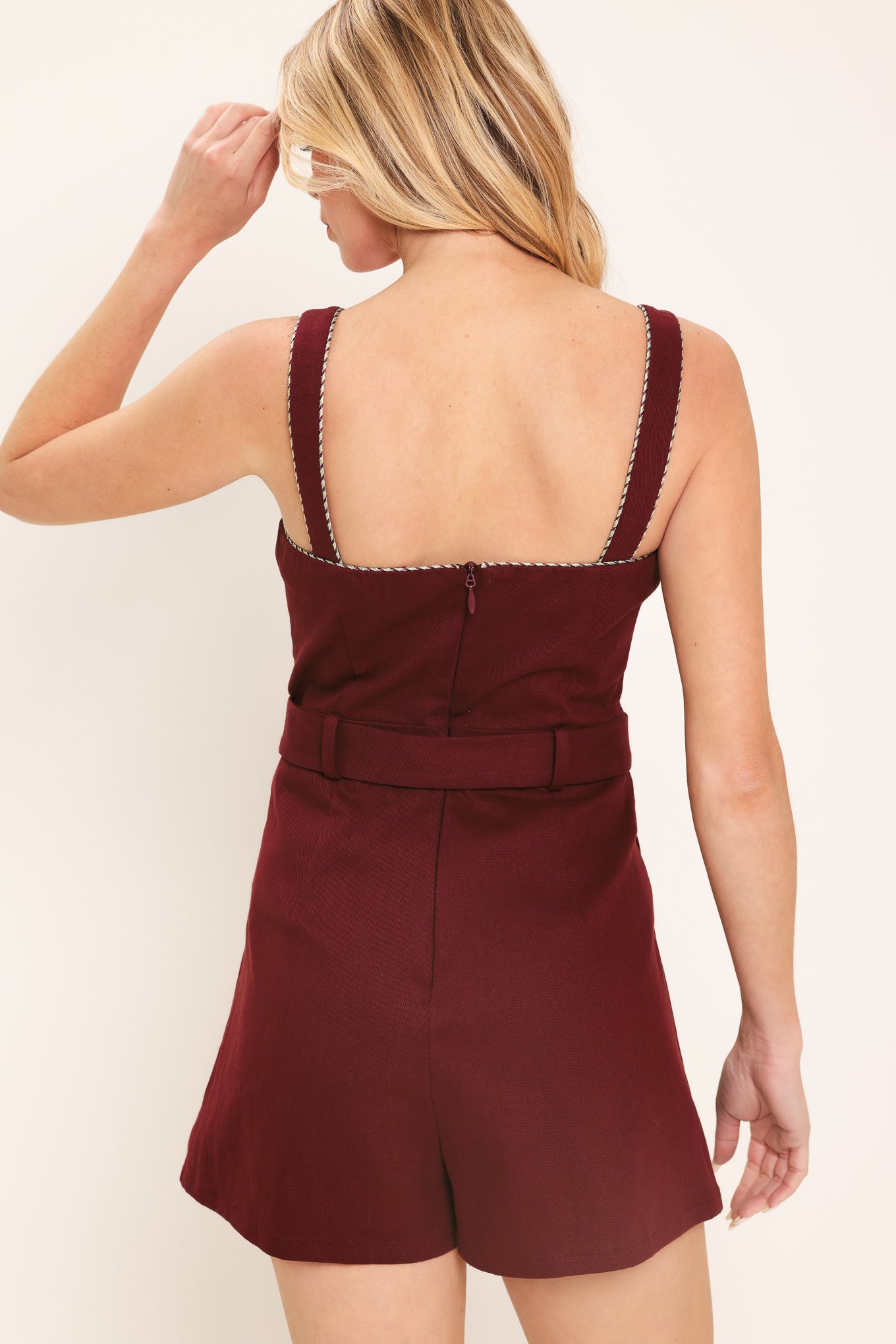 Woman wearing a burgundy romper with buttons and a belt | Flying Tomato