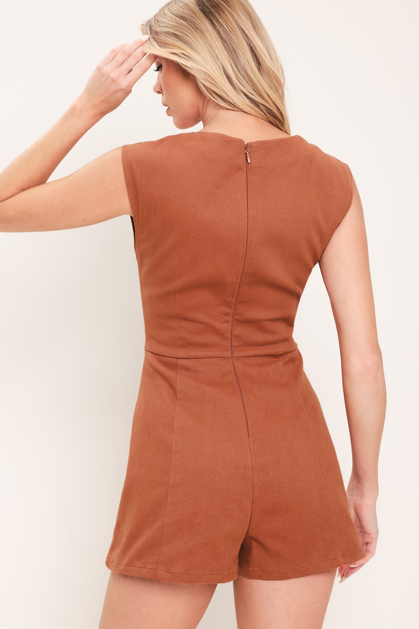 Woman wearing a rust-colored romper featuring square neckline, sleeveless, front button detail and back zipper closure | Flying Tomato