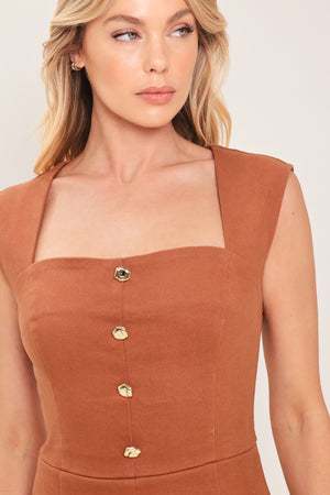 Woman wearing a rust-colored romper featuring square neckline, sleeveless, front button detail and back zipper closure | Flying Tomato