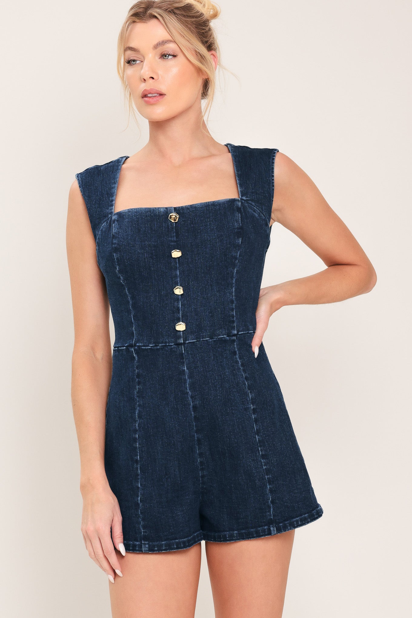 Woman wearing a denim romper featuring square neckline, sleeveless, front button detail and back zipper closure | Flying Tomato
