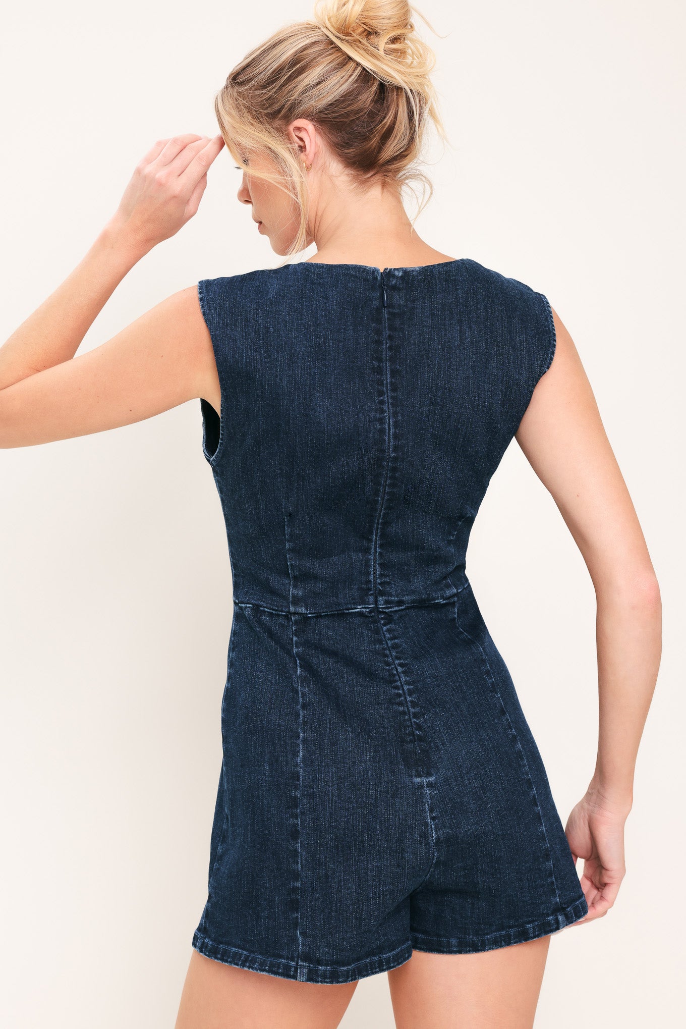 Woman wearing a denim romper featuring square neckline, sleeveless, front button detail and back zipper closure | Flying Tomato