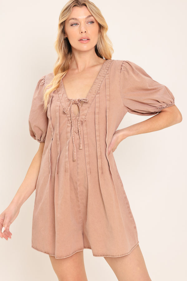 Woman wearing a light peach toned romper with puff sleeves and v-cut with bows | Flying Tomato