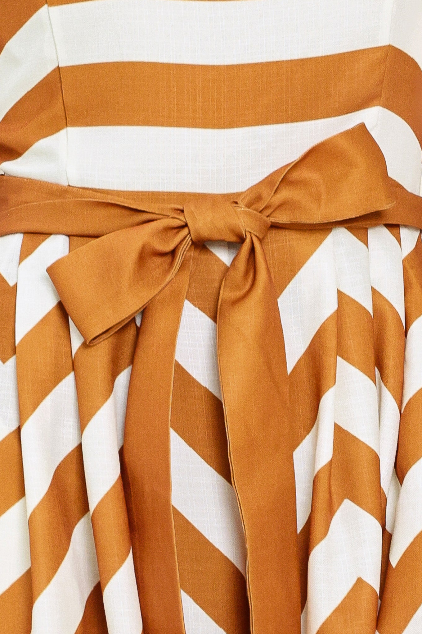 Woman wearing a camel and white strapless, long chevron-patterned jumpsuit featuring solid tie, wide leg and smocked back bodice | Flying Tomato