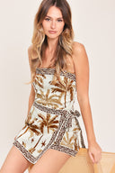 Woman wearing a strapless skort romper with palm tree pattern and geometric detail | Flying Tomato