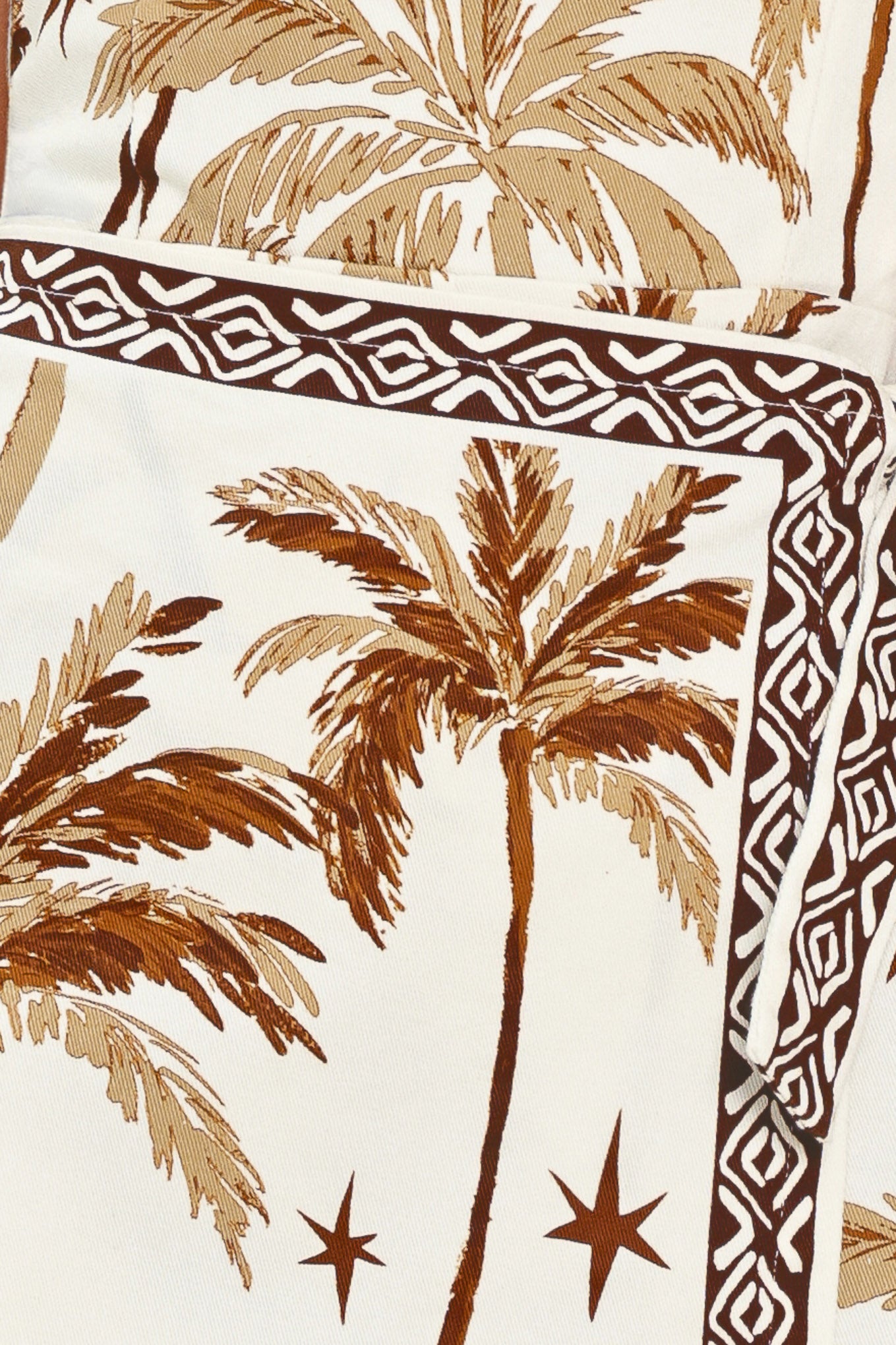 Woman wearing a strapless skort romper with palm tree pattern and geometric detail | Flying Tomato