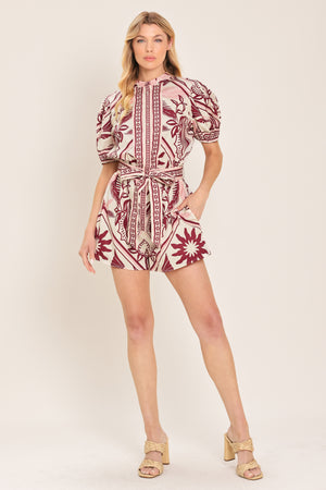 Woman wearing a burgundy patterned romper with a self tie | Flying Tomato