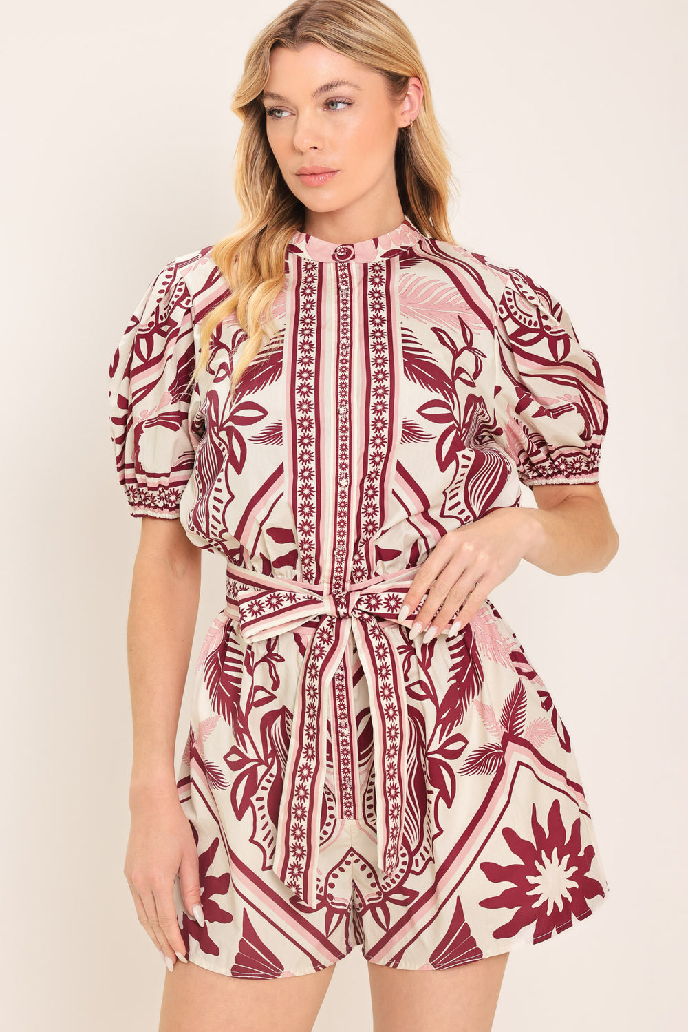 Woman wearing a burgundy patterned romper with a self tie | Flying Tomato