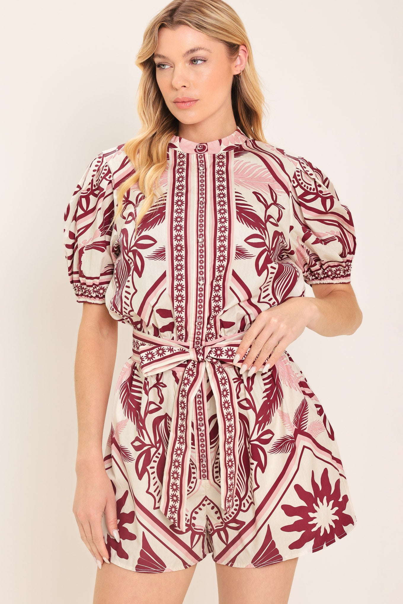 Woman wearing a burgundy patterned romper with a self tie | Flying Tomato