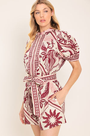 Woman wearing a burgundy patterned romper with a self tie | Flying Tomato