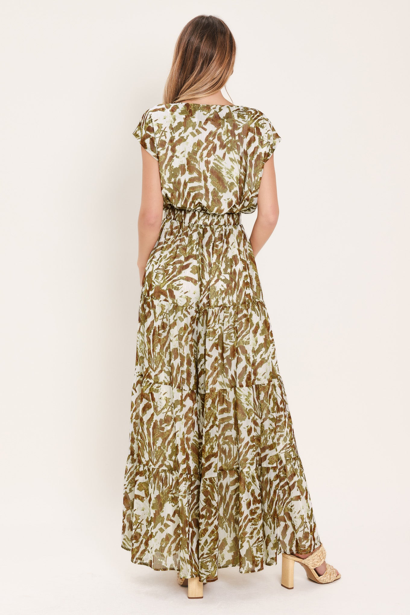 Woman wearing an olive green, brown, and white patterned woven jumpsuit featuring round neckline, short sleeve, front tie detail, elastic waist and tier wide leg pant | Flying Tomato