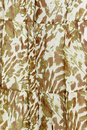Woman wearing an olive green, brown, and white patterned woven jumpsuit featuring round neckline, short sleeve, front tie detail, elastic waist and tier wide leg pant | Flying Tomato