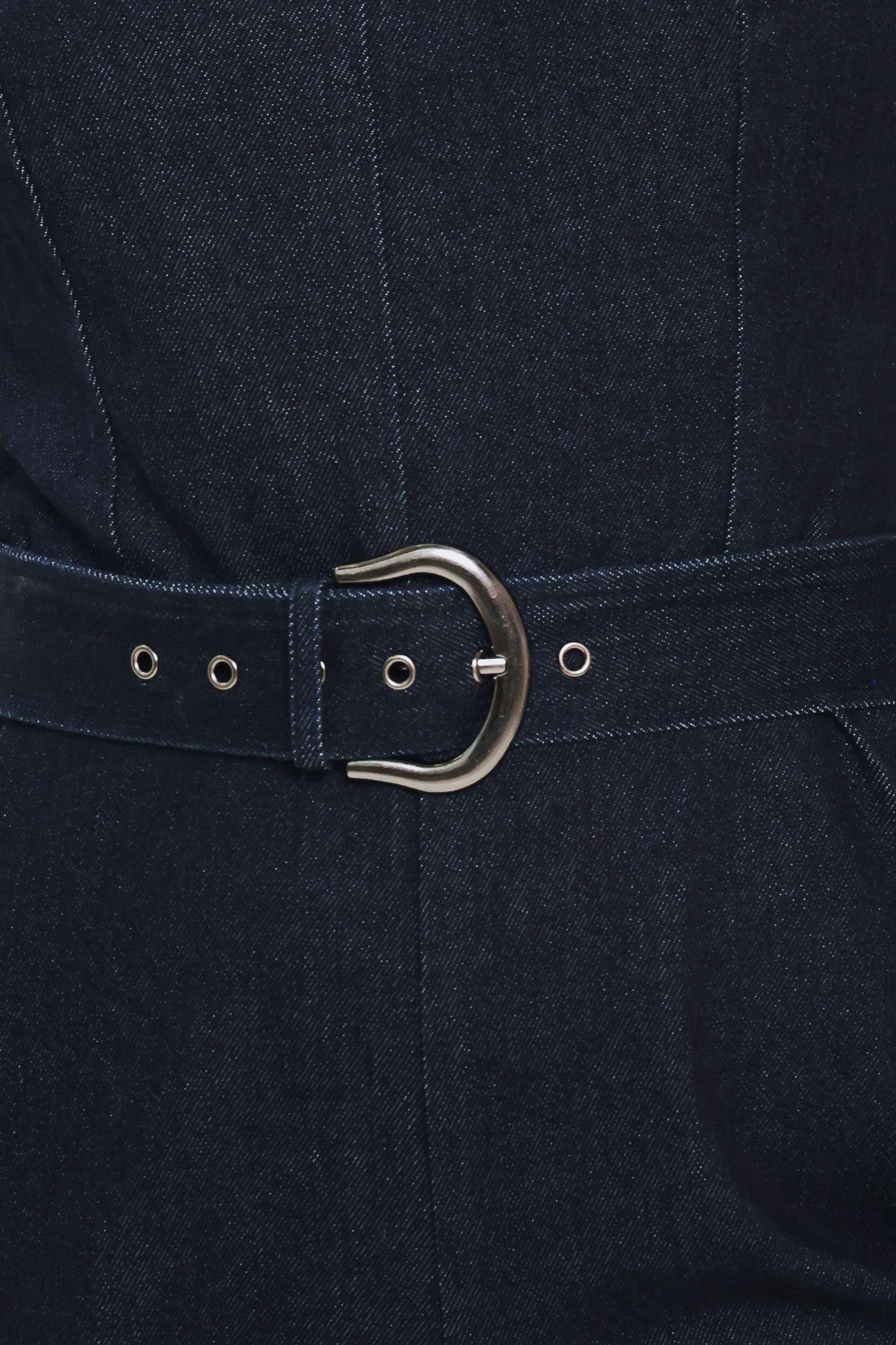 Woman wearing a dark indigo denim jumpsuit featuring sweetheart neckline, sleeveless, self belt, wide leg and back zipper closure | Flying Tomato