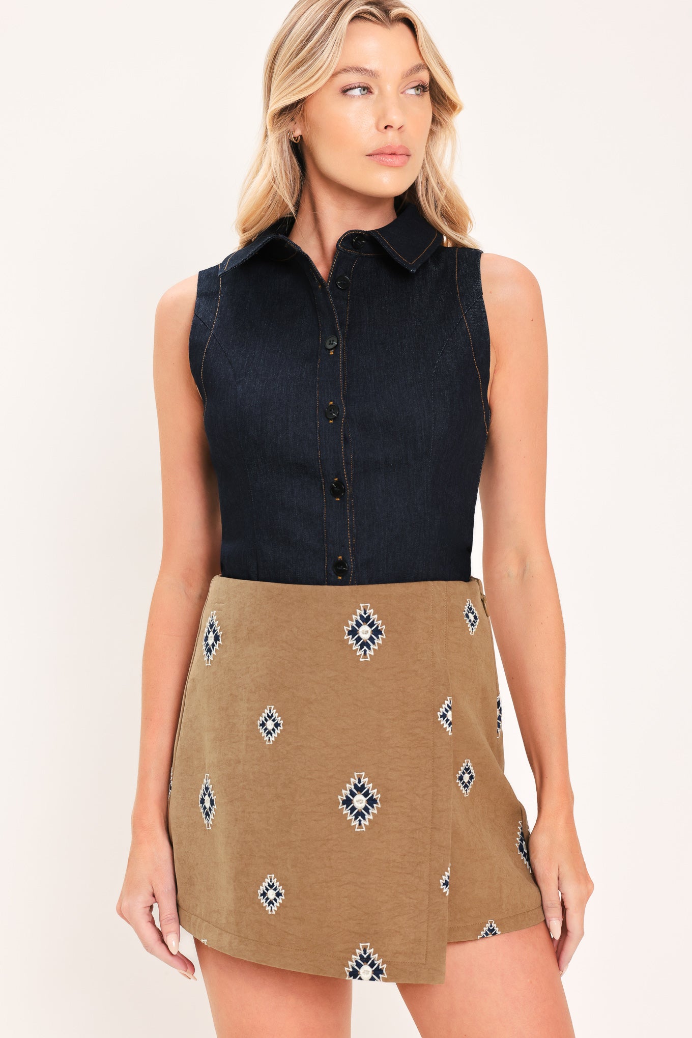 A woman wearing a camel wrap-style mini skort with a navy and white geometric diamond pattern | Flying Tomato
